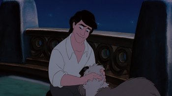 Movie still from “The Little Mermaid” (1989), directed by John Musker – A man holding a cat in front of a fence; Medium shot, Low angle