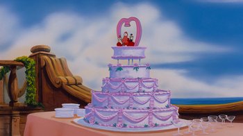 Movie still from “The Little Mermaid” (1989), directed by John Musker – A large wedding cake with a pink heart on the top of it; Wide shot, High angle