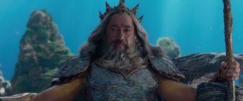 Movie still from “The Little Mermaid” (2023), directed by Rob Marshall – A man with long hair and a beard wearing a crown; Close Up shot, Low angle