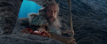 Movie still from “The Little Mermaid” (2023), directed by Rob Marshall – A man with a beard and a crown holding a staff; Medium shot, High angle
