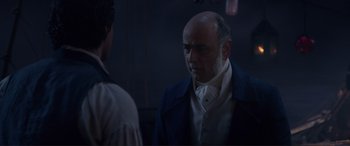 Movie still from “The Little Mermaid” (2023), directed by Rob Marshall – A man with a bald head talking to another man in a suit; Close Up shot, Over the shoulder angle
