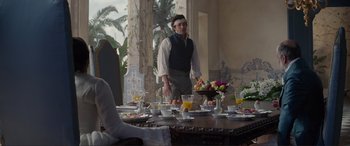 Movie still from “The Little Mermaid” (2023), directed by Rob Marshall – A man standing in front of a dining room table; Medium shot, Over the shoulder angle