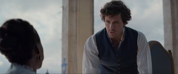 Movie still from “The Little Mermaid” (2023), directed by Rob Marshall – A man wearing a vest and standing in front of a pillar; Close Up shot, Over the shoulder angle