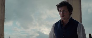 Movie still from “The Little Mermaid” (2023), directed by Rob Marshall – A man wearing a vest standing in front of a cloudy sky; Close Up shot, Over the shoulder angle