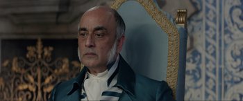 Movie still from “The Little Mermaid” (2023), directed by Rob Marshall – An older man in a blue suit and white shirt; Close Up shot, Over the shoulder angle