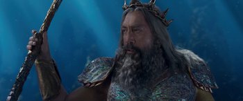Movie still from “The Little Mermaid” (2023), directed by Rob Marshall – A man with long hair and a beard wearing a crown; Close Up shot, Low angle