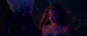 Movie still from “The Little Mermaid” (2023), directed by Rob Marshall – A woman with long hair is standing in the dark; Close Up shot, Over the shoulder angle