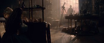 Movie still from “The Little Mermaid” (2023), directed by Rob Marshall – A person standing in a room with a telescope; Wide shot, High angle