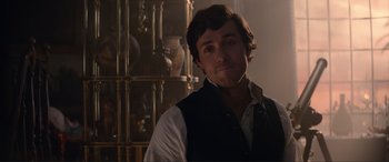Movie still from “The Little Mermaid” (2023), directed by Rob Marshall – A man in a vest standing next to a table; Close Up shot, Over the shoulder angle