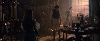 Movie still from “The Little Mermaid” (2023), directed by Rob Marshall – A man standing next to a woman in front of a table; Wide shot, Over the shoulder angle