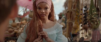 Movie still from “The Little Mermaid” (2023), directed by Rob Marshall – A young girl with long red dreadlocks and a pink head scarf; Close Up shot, Low angle