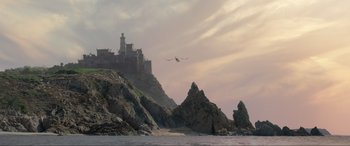 Movie still from “The Little Mermaid” (2023), directed by Rob Marshall – A bird flying over a body of water with a castle in the background; Extreme Wide shot, High angle