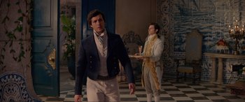 Movie still from “The Little Mermaid” (2023), directed by Rob Marshall – A man in a suit stands in front of another man in a suit; Medium shot, Over the shoulder angle