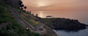 Movie still from “The Little Mermaid” (2023), directed by Rob Marshall – A group of people walking up a hill at sunset; Extreme Wide shot, High angle