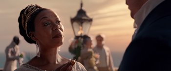Movie still from “The Little Mermaid” (2023), directed by Rob Marshall – An older woman standing in front of a street light; Close Up shot, Over the shoulder angle
