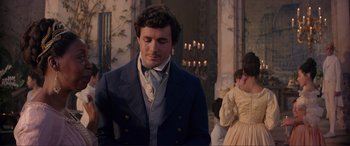 Movie still from “The Little Mermaid” (2023), directed by Rob Marshall – A man in a blue suit standing in front of candles; Medium shot, Over the shoulder angle