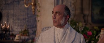 Movie still from “The Little Mermaid” (2023), directed by Rob Marshall – An older man in a white suit looking to his left; Close Up shot, Over the shoulder angle