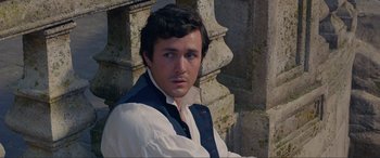 Movie still from “The Little Mermaid” (2023), directed by Rob Marshall – A man in a white shirt and a blue vest standing in front of a wall; Close Up shot, High angle