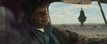 Movie still from “The Locksmith” (2023), directed by Nicolas Harvard – An older man sitting in the passenger seat of a car; Close Up shot, Over the shoulder angle