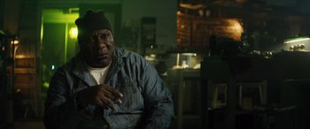 Movie still from “The Locksmith” (2023), directed by Nicolas Harvard – A man sitting in a room smoking a cigarette; Close Up shot, Low angle