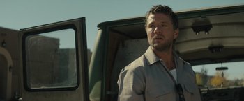 Movie still from “The Locksmith” (2023), directed by Nicolas Harvard – A person standing next to a truck; Close Up shot, Over the shoulder angle