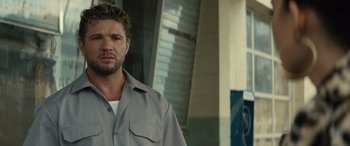 Movie still from “The Locksmith” (2023), directed by Nicolas Harvard – A person wearing a shirt; Close Up shot, Low angle