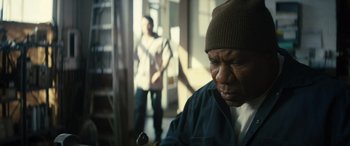 Movie still from “The Locksmith” (2023), directed by Nicolas Harvard – An older man wearing a hat is looking at the camera; Close Up shot, Low angle