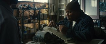 Movie still from “The Locksmith” (2023), directed by Nicolas Harvard – A man working in a workshop on a piece of metal; Close Up shot, Low angle