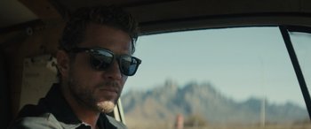 Movie still from “The Locksmith” (2023), directed by Nicolas Harvard – A person in a car wearing sunglasses; Close Up shot, Over the shoulder angle