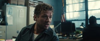 Movie still from “The Locksmith” (2023), directed by Nicolas Harvard – A person with curly hair in a room; Close Up shot, Over the shoulder angle