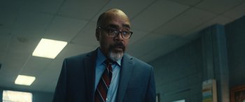 Movie still from “The Locksmith” (2023), directed by Nicolas Harvard – A man in a blue suit and a red tie; Close Up shot, Over the shoulder angle