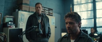 Movie still from “The Locksmith” (2023), directed by Nicolas Harvard – Two men standing next to each other in a room; Medium shot, Over the shoulder angle