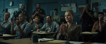Movie still from “The Locksmith” (2023), directed by Nicolas Harvard – A group of people sitting at a table; Medium shot, Over the shoulder angle