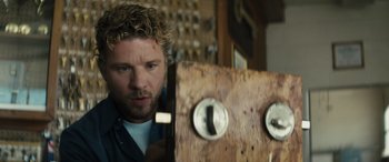 Movie still from “The Locksmith” (2023), directed by Nicolas Harvard – A person with a wooden object; Close Up shot, Low angle