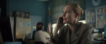 Movie still from “The Locksmith” (2023), directed by Nicolas Harvard – A woman talking on a cell phone in an office setting; Close Up shot, Over the shoulder angle