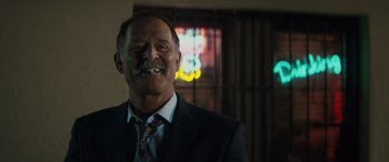 Movie still from “The Locksmith” (2023), directed by Nicolas Harvard – A person wearing a suit and tie; Close Up shot, Low angle