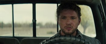 Movie still from “The Locksmith” (2023), directed by Nicolas Harvard – A person sitting in a car holding a steering wheel; Close Up shot, Over the shoulder angle