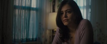 Movie still from “The Locksmith” (2023), directed by Nicolas Harvard – A person sitting in a room near a window; Close Up shot, Over the shoulder angle