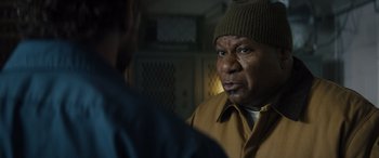 Movie still from “The Locksmith” (2023), directed by Nicolas Harvard – A man in a hat is talking to another man; Close Up shot, Over the shoulder angle