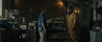 Movie still from “The Locksmith” (2023), directed by Nicolas Harvard – Two men standing next to each other in a room; Medium shot, Over the shoulder angle