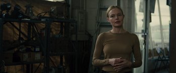 Movie still from “The Locksmith” (2023), directed by Nicolas Harvard – A woman standing in front of a building; Medium shot, Over the shoulder angle