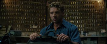 Movie still from “The Locksmith” (2023), directed by Nicolas Harvard – A man in a blue shirt is holding a steering wheel; Close Up shot, High angle