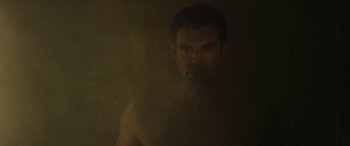 Movie still from “The Locksmith” (2023), directed by Nicolas Harvard – A shirtless man in a dimly - lit room; Close Up shot, Low angle