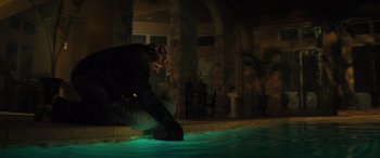 Movie still from “The Locksmith” (2023), directed by Nicolas Harvard – A man kneeling on the ground with a flashlight; Wide shot, High angle