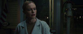 Movie still from “The Locksmith” (2023), directed by Nicolas Harvard – A woman in a white jacket is looking at the camera; Close Up shot, Over the shoulder angle