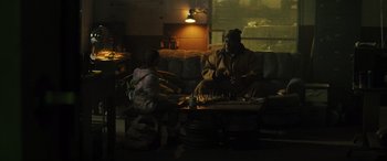 Movie still from “The Locksmith” (2023), directed by Nicolas Harvard – A man and a woman playing a game of chess on a couch; Wide shot, Over the shoulder angle