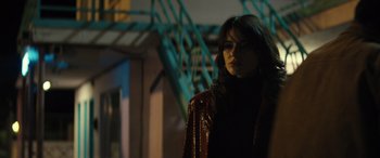 Movie still from “The Locksmith” (2023), directed by Nicolas Harvard – A woman in a red jacket standing in front of a building; Close Up shot, Low angle