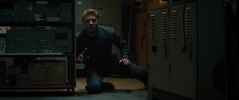 Movie still from “The Locksmith” (2023), directed by Nicolas Harvard – A man kneeling on the ground in a room; Medium shot, Low angle