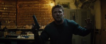 Movie still from “The Locksmith” (2023), directed by Nicolas Harvard – A man is holding a gun in a room; Close Up shot, Over the shoulder angle