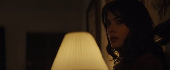 Movie still from “The Locksmith” (2023), directed by Nicolas Harvard – A person near a lamp in a room; Close Up shot, Over the shoulder angle